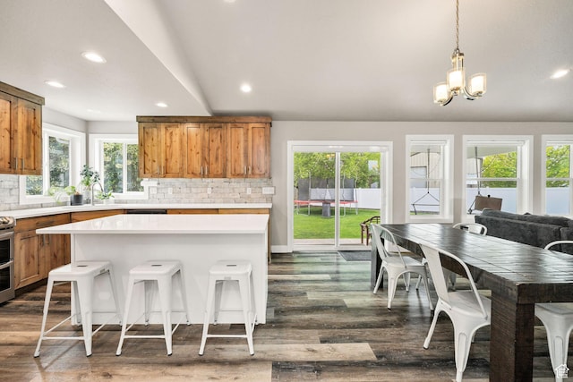 kitchen with brown cabinetry, light countertops, backsplash, dark wood-style flooring, and recessed lighting