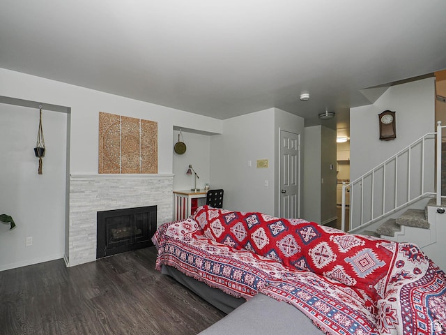bedroom featuring wood finished floors, a tiled fireplace, and baseboards