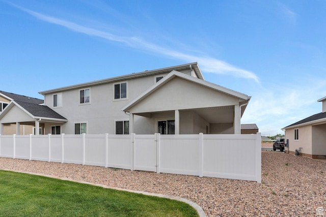 rear view of house featuring fence and stucco siding
