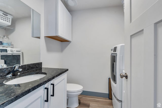 bathroom featuring washer / clothes dryer, wood finished floors, vanity, toilet, and baseboards
