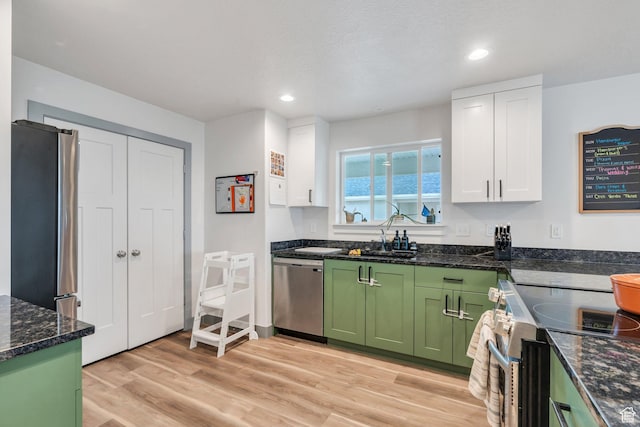 kitchen featuring green cabinetry, stainless steel appliances, a sink, white cabinetry, and light wood finished floors