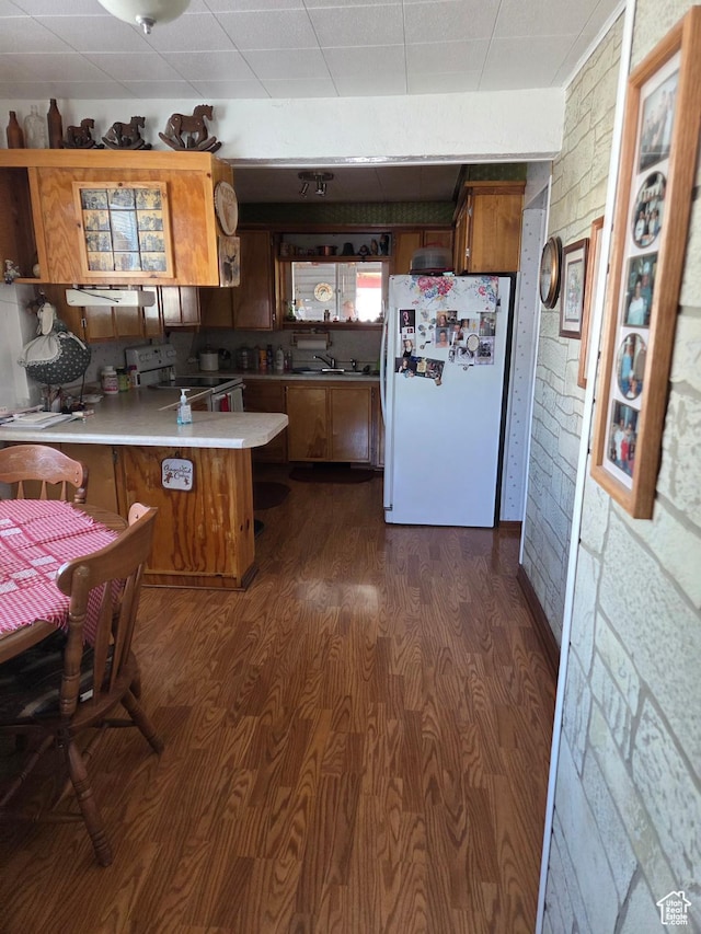 157 E 100 N, Wellington, UT 84542 - kitchen with white appliances, a peninsula, brown cabinets, dark wood finished floors, and light countertops