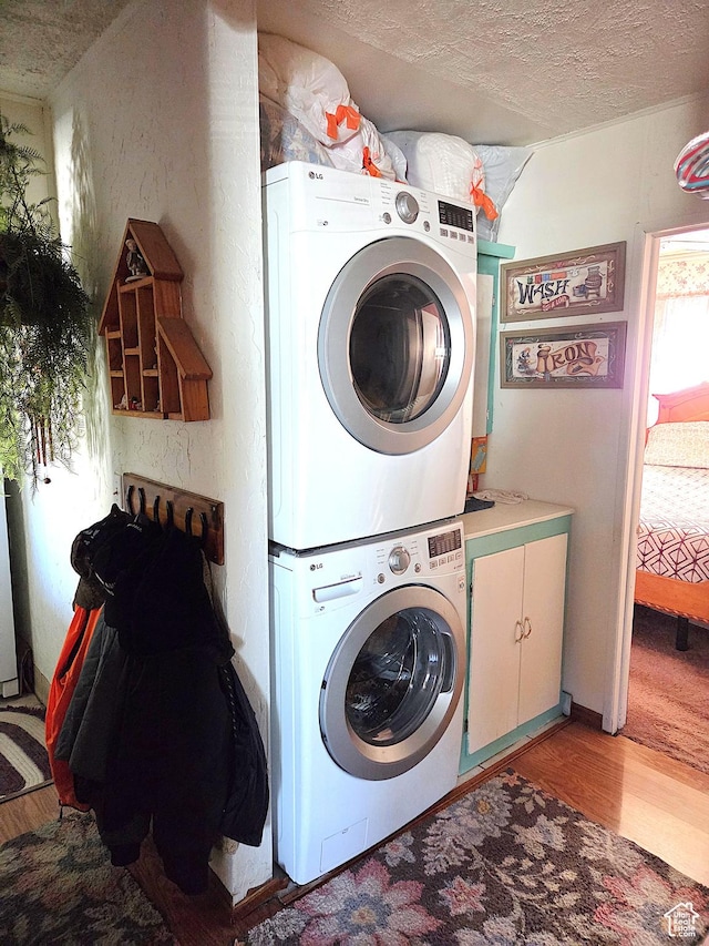 157 E 100 N, Wellington, UT 84542 - laundry room featuring stacked washing machine and dryer, cabinet space, light wood finished floors, and a textured ceiling