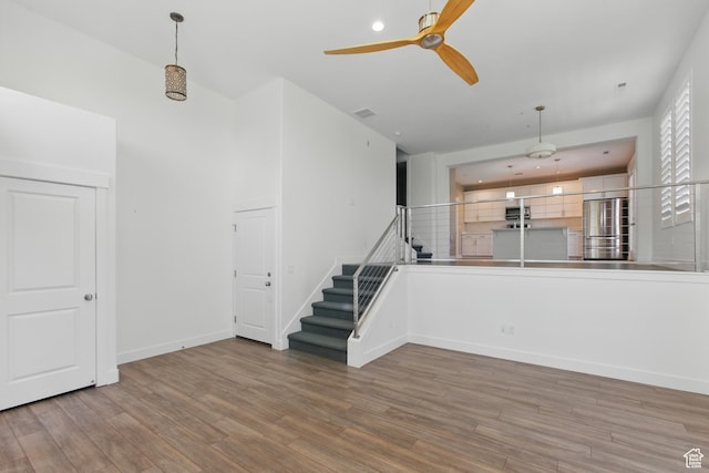 4955 W Daybreak Pkwy, South Jordan, UT 84009 - unfurnished living room with ceiling fan, wood finished floors, baseboards, and stairs