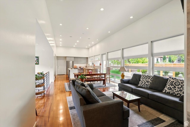 living area with recessed lighting, a high ceiling, and light wood-style flooring