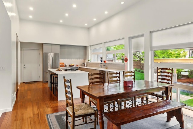 dining space featuring a high ceiling, plenty of natural light, recessed lighting, and light wood finished floors