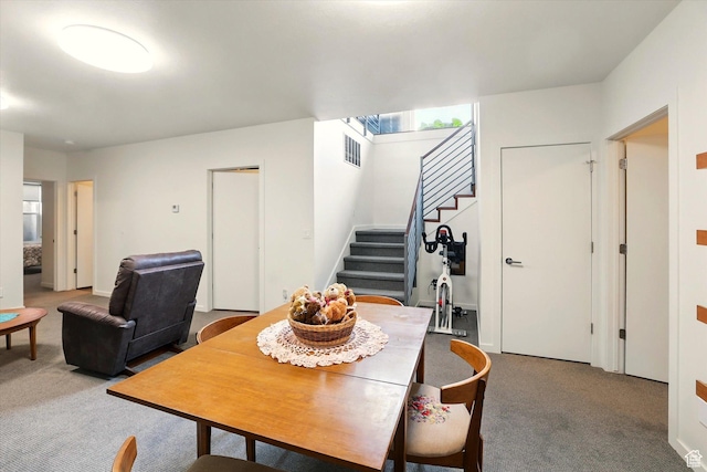 carpeted dining room featuring stairway