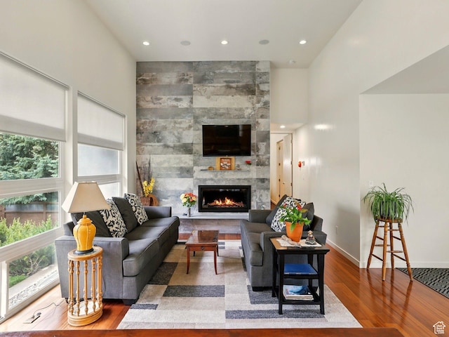 living room featuring wood finished floors, a tiled fireplace, baseboards, and recessed lighting
