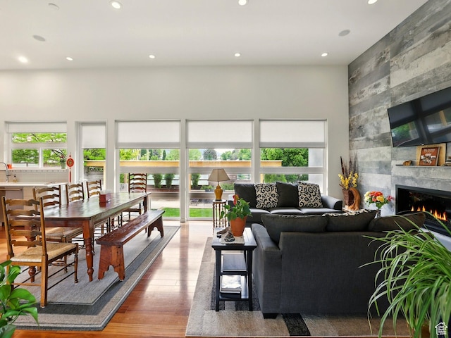 living room featuring wood finished floors, recessed lighting, a tiled fireplace, and a high ceiling