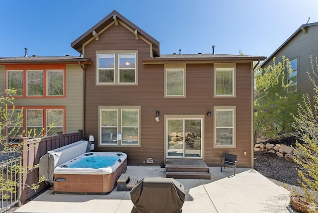 rear view of house featuring a hot tub and a patio area