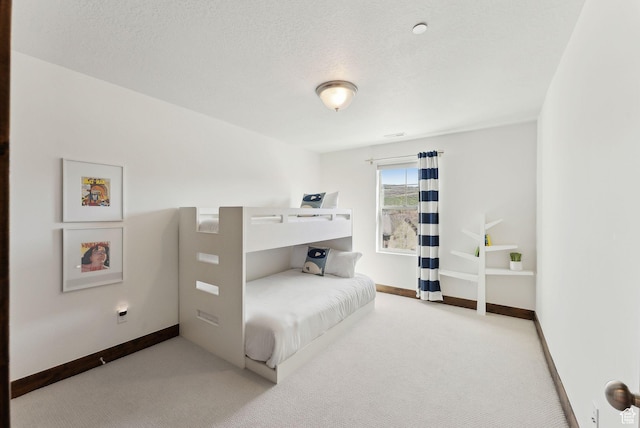 bedroom with carpet floors, baseboards, and a textured ceiling