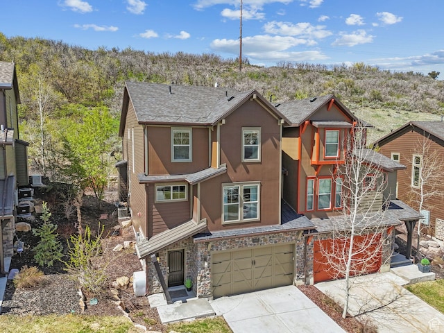 view of front of house featuring driveway, stone siding, a garage, and stucco siding