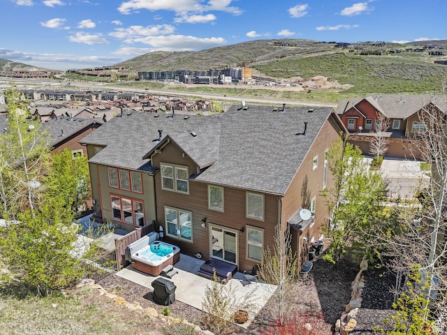 rear view of house with a mountain view, a patio area, a shingled roof, and fence