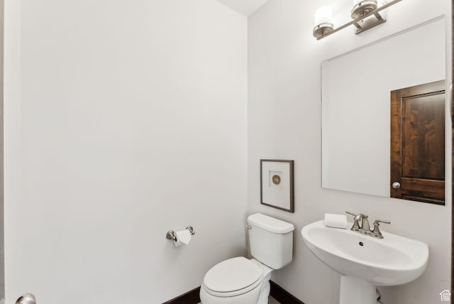 half bathroom featuring a sink, toilet, and baseboards