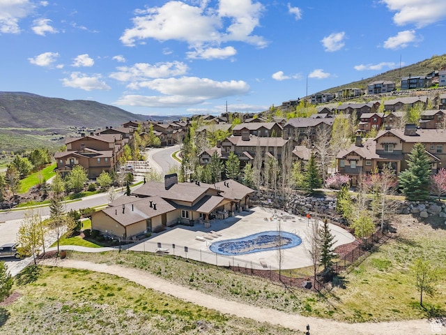 aerial view of residential area featuring a mountainous background and a pool area