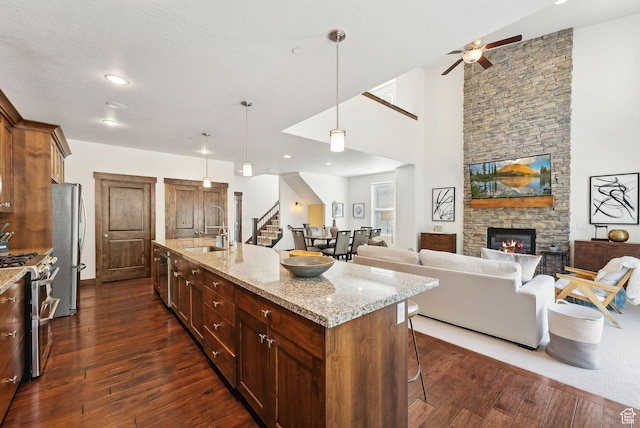 kitchen with stainless steel appliances, a sink, a kitchen breakfast bar, dark wood-style floors, and ceiling fan