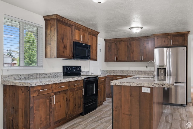 6594 S 1300 W, Taylorsville, UT 84123 - kitchen with black appliances, a sink, a center island with sink, a textured ceiling, and light stone counters