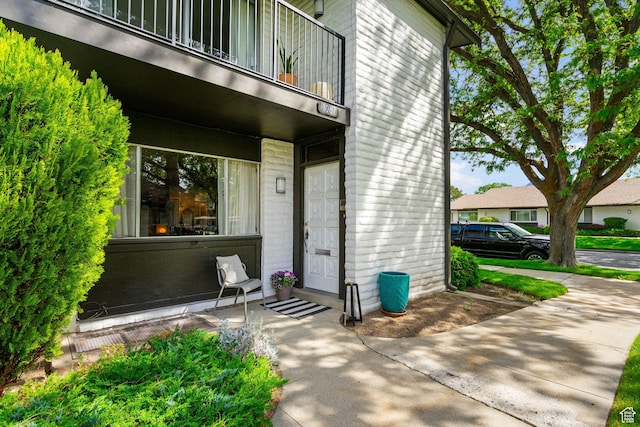 doorway to property featuring a balcony and brick siding