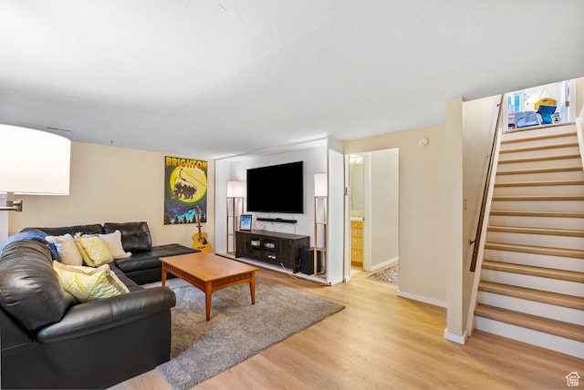 living area with light wood-type flooring, stairs, and baseboards