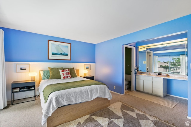 bedroom with light carpet and wainscoting
