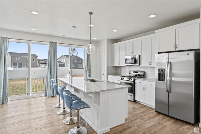6405 N Appaloosa Dr, Stansbury Park, UT 84074 - kitchen featuring appliances with stainless steel finishes, a sink, white cabinets, an island with sink, and recessed lighting