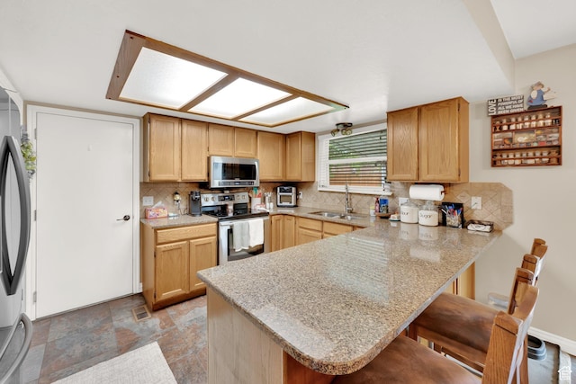 2298 W Jordan Meadows Cv, West Jordan, UT 84084 - kitchen with appliances with stainless steel finishes, a sink, a peninsula, decorative backsplash, and a breakfast bar area