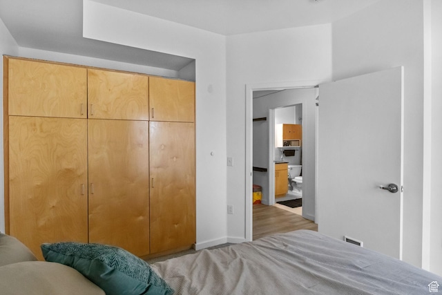 bedroom with wood finished floors, a closet, and baseboards