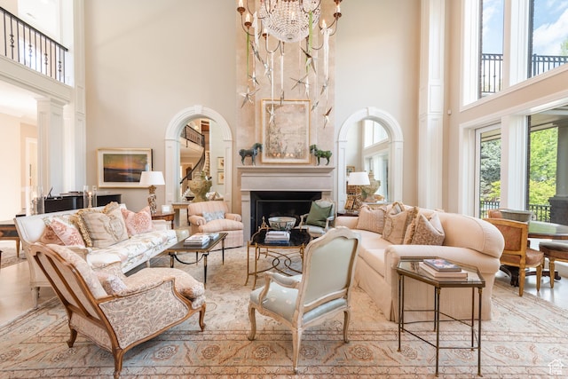 living area featuring a towering ceiling, a fireplace, and a chandelier