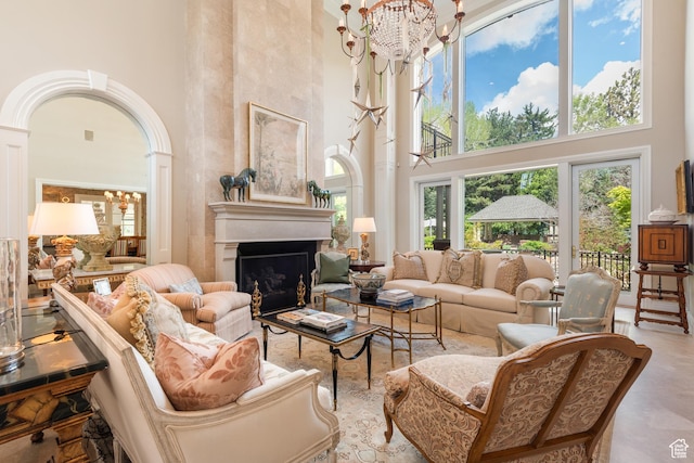 living area with a high ceiling, a chandelier, a fireplace, and ornate columns