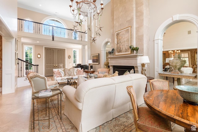 living room featuring a high ceiling, a chandelier, arched walkways, stairs, and crown molding
