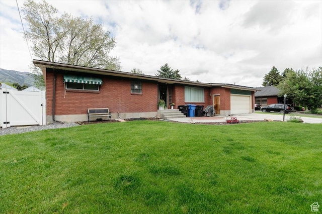 ranch-style home with a gate, brick siding, an attached garage, and a front yard