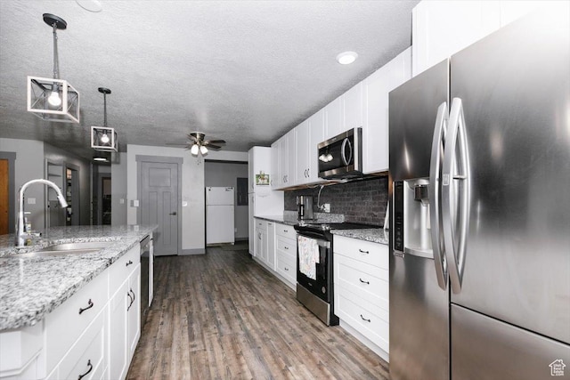 kitchen featuring stainless steel appliances, a sink, white cabinets, decorative backsplash, and wood finished floors