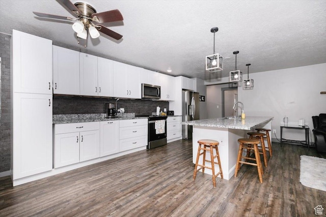 kitchen featuring appliances with stainless steel finishes, dark wood-type flooring, a sink, a kitchen bar, and white cabinets