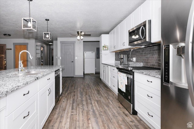 kitchen featuring appliances with stainless steel finishes, a sink, decorative backsplash, white cabinetry, and a textured ceiling