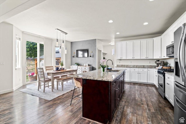 kitchen with stainless steel appliances, a sink, dark wood-style floors, white cabinets, and recessed lighting