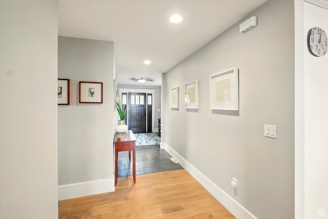 hall featuring baseboards, recessed lighting, and wood finished floors