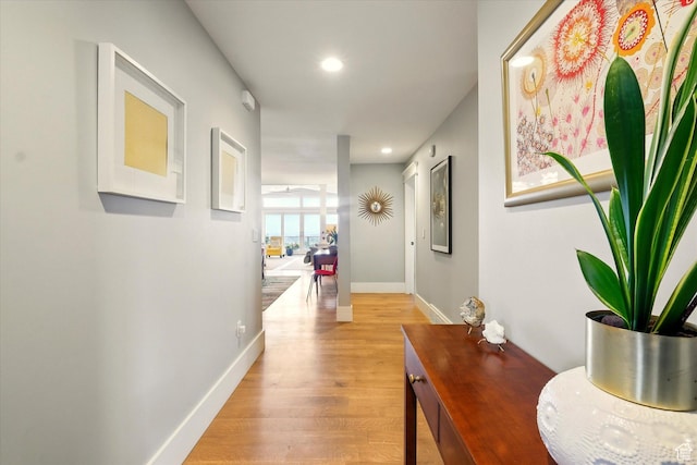 corridor featuring light wood-type flooring, baseboards, and recessed lighting