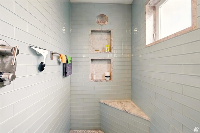 bathroom with a tile shower and tile walls