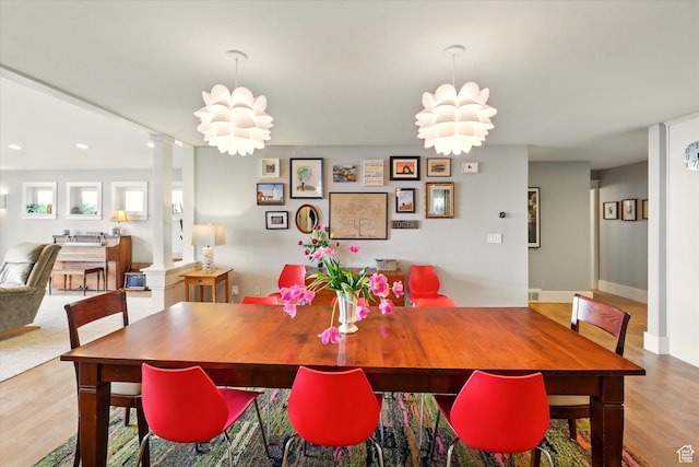 dining area with wood finished floors, decorative columns, baseboards, and a chandelier