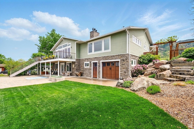 rear view of house with stairs, a patio, stone siding, a yard, and a chimney