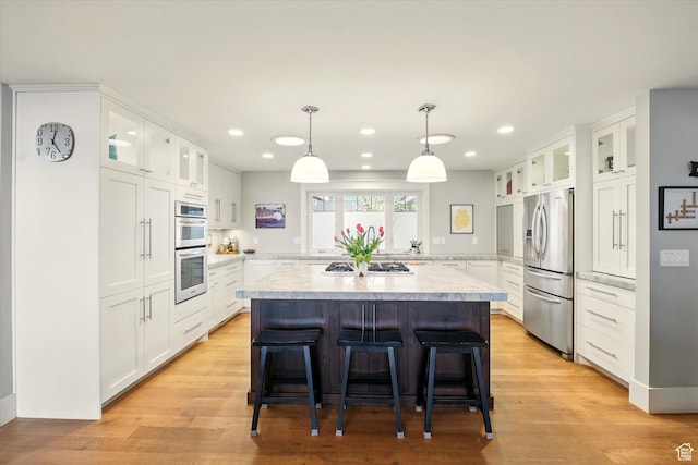 kitchen with stainless steel appliances, light countertops, a center island, recessed lighting, and a kitchen breakfast bar