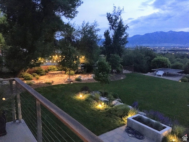 view of green lawn featuring a patio area and a mountain view