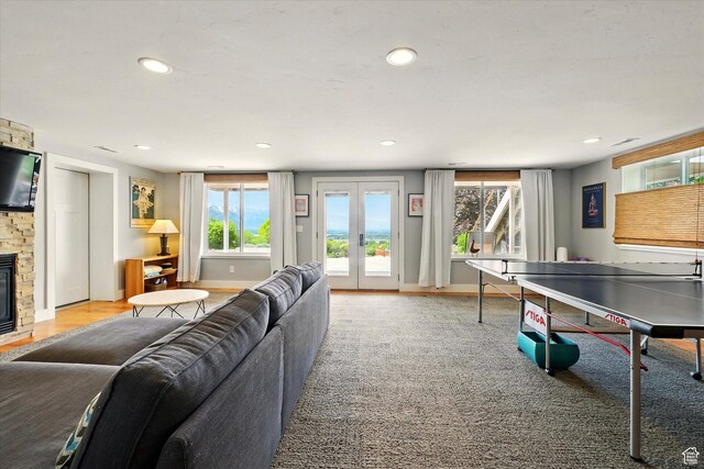 recreation room featuring plenty of natural light, a stone fireplace, recessed lighting, and french doors