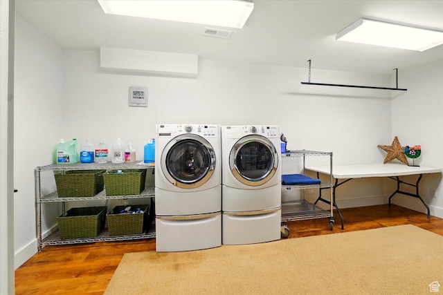 laundry area with wood finished floors, washing machine and dryer, and baseboards