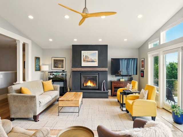 living room with ceiling fan, a large fireplace, recessed lighting, vaulted ceiling, and decorative columns