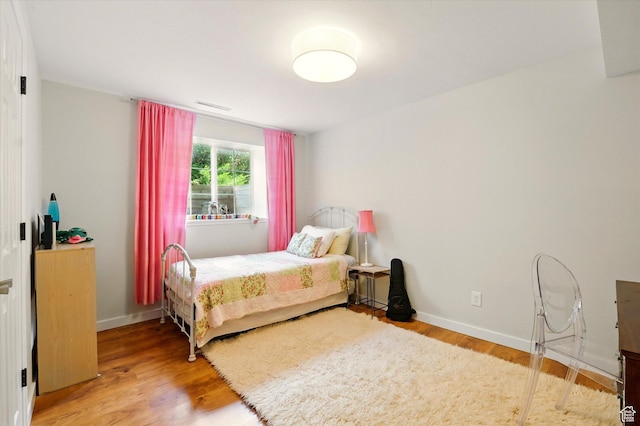bedroom featuring light wood finished floors and baseboards