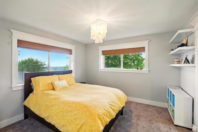 carpeted bedroom featuring baseboards and a chandelier