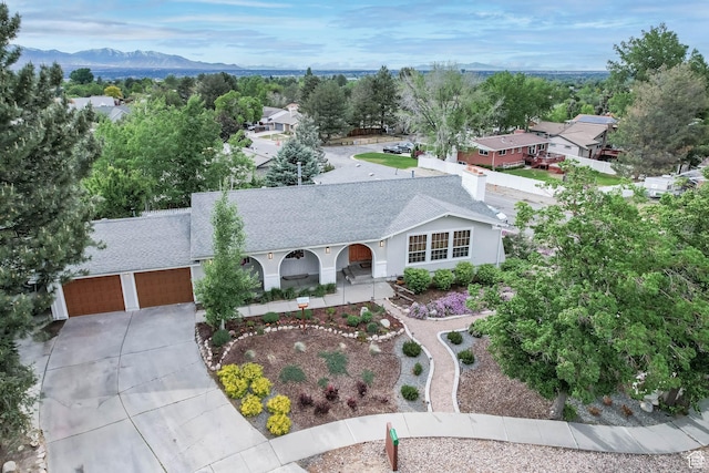 view of front facade featuring driveway, roof with shingles, a mountain view, and a garage
