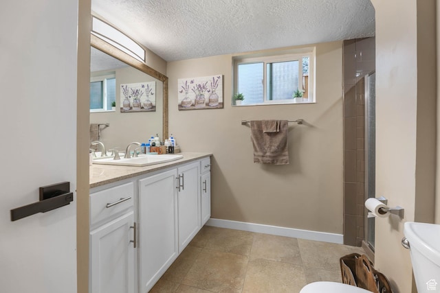 bathroom featuring toilet, a textured ceiling, vanity, and baseboards