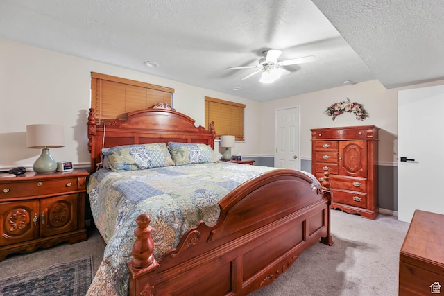 bedroom featuring light carpet, a ceiling fan, and a textured ceiling